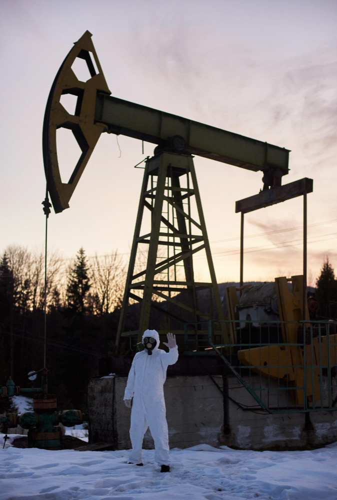 Ecologist standing near oil well pump jack